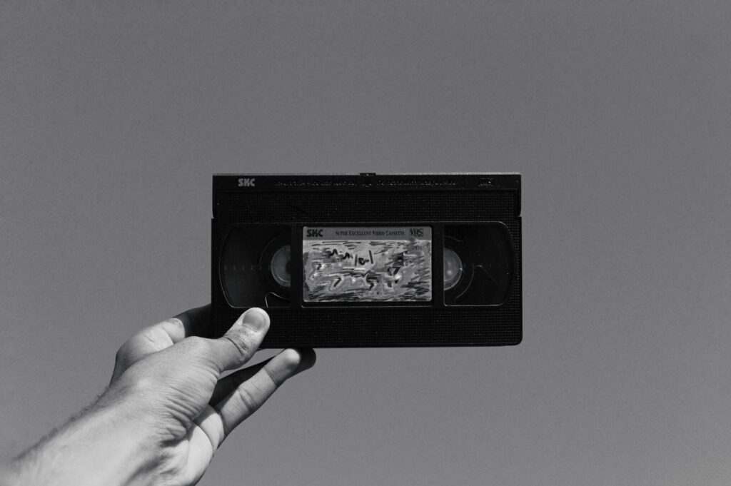 Eine Hand hält eine alte VHS-Kassette gegen den Himmel. Ideal, um VHS digitalisieren und wertvolle Erinnerungen zu bewahren.