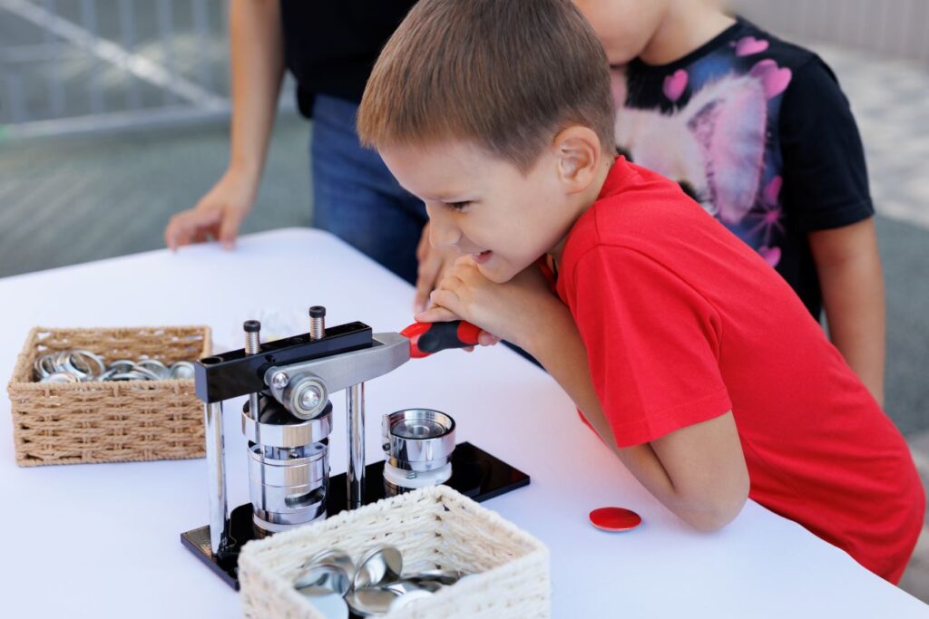 Junge presst Button mit Bastelmaschine – Buttons bestellen fuer DIY-Projekte mit Kindern, Schulaktionen oder kreative Gruppenarbeit