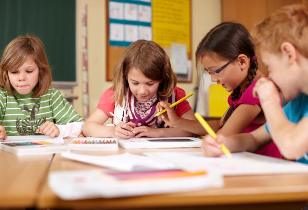 Grundschulkinder malen und schreiben gemeinsam im Klassenraum – Darstellung von Lernumgebung und kosten privatschule berlin