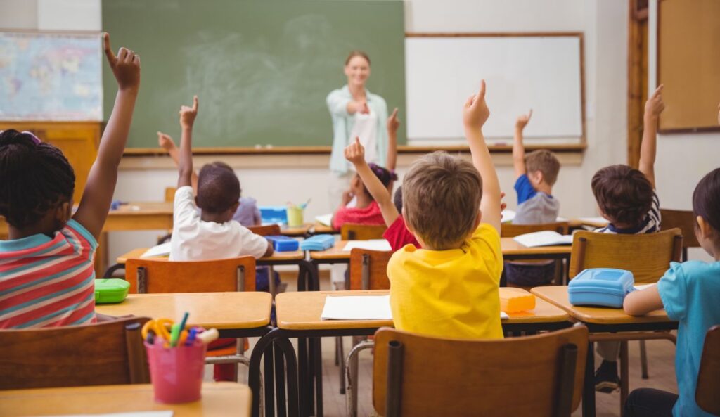 Kinder heben die Haende im Unterricht – Symbolbild fuer Engagement, Foerderung und kosten privatschule berlin