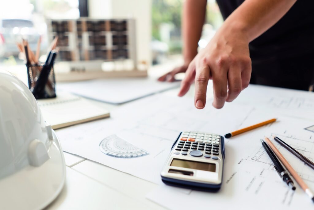 Hände und Taschenrechner auf Bauplänen | Porenbetonschrauben